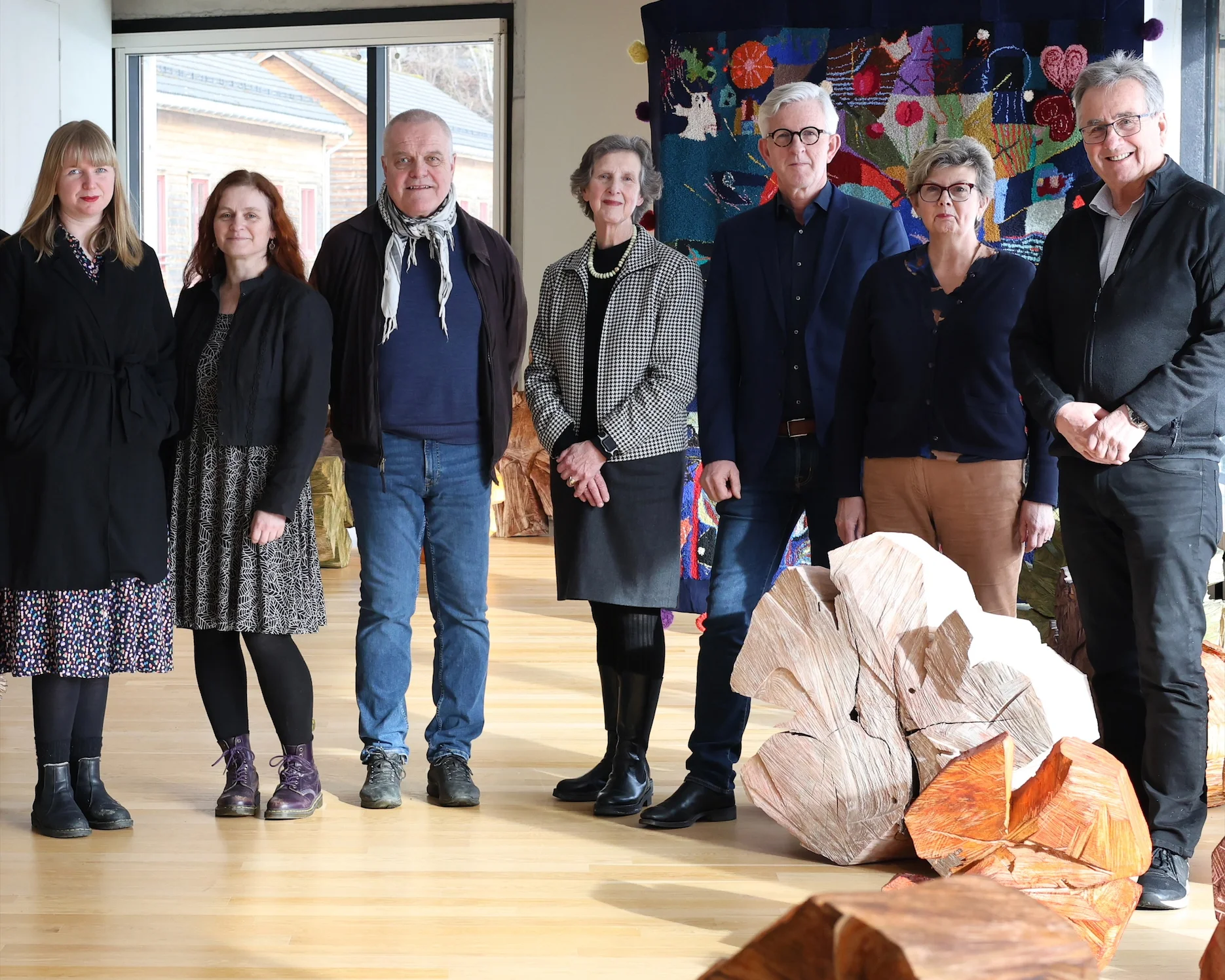 fire kvinner og tre menni styret til Hardanger og voss museum står i et rom med kunst på gulvet og som et bakteppe