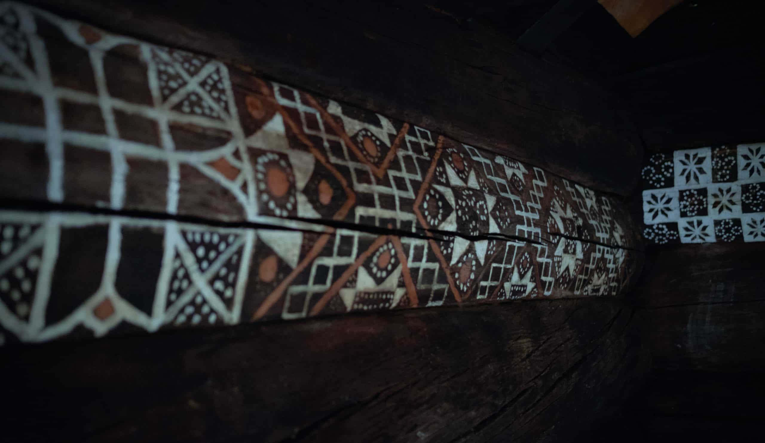 Krotede mønster i hvitt på en gammel laftevegg.